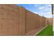 Tan brick backyard fence with grass and gravel landscaping under a blue sky at 4412 N 203Rd Dr, Buckeye, AZ 85396