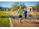 Couple walking their dog on a paved path in a residential area at 4412 N 203Rd Dr, Buckeye, AZ 85396