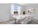 Bright dining room featuring a modern white table with seating for six, illuminated by natural light from a large window at 9054 S 169Th Dr, Goodyear, AZ 85338