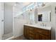 Bright bathroom featuring double sinks, hardwood cabinet, mirrors, and a stand up shower at 14701 W Sentinel Dr, Sun City West, AZ 85375