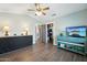 Bedroom with wood floors, ceiling fan, adjacent storage closet, and TV on blue cabinet at 14701 W Sentinel Dr, Sun City West, AZ 85375