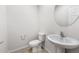 Powder room features pedestal sink, round mirror, toilet, and tile flooring at 17857 W Getty Dr, Goodyear, AZ 85338