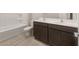 Bathroom with double sinks, dark cabinets, and tub with tile surround at 17875 W Getty Dr, Goodyear, AZ 85338