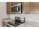 Close-up of kitchen featuring stainless steel appliances, granite countertops, and wood cabinets at 17875 W Getty Dr, Goodyear, AZ 85338