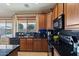 Charming kitchen showcasing wood cabinetry, black appliances, and a scenic window view at 18017 W Desert Ln, Surprise, AZ 85388