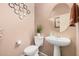 Cozy half bathroom with a pedestal sink, decorative mirror, and neutral wall color at 21134 W Sunrise Ln, Buckeye, AZ 85396