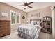 Cozy bedroom with a queen-size bed, ceiling fan, and natural light streaming through shuttered windows at 21134 W Sunrise Ln, Buckeye, AZ 85396