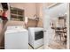 Laundry room with white washer and dryer, window, shelf, and view to kitchen at 21134 W Sunrise Ln, Buckeye, AZ 85396
