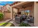 Relaxing covered outdoor patio with wicker furniture, ceiling fan, mounted TV, grill, and well-manicured landscaping at 21134 W Sunrise Ln, Buckeye, AZ 85396