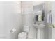 Bright white powder room featuring pedestal sink, toilet, and shuttered window at 42017 N Crooked Stick Rd, Anthem, AZ 85086