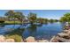 A tranquil community pond with a gazebo, and rocky shore, creating a peaceful recreation space on a sunny day at 42017 N Crooked Stick Rd, Anthem, AZ 85086