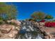 Beautiful community waterfall cascading over rocks surrounded by lush greenery, providing a serene natural setting at 42017 N Crooked Stick Rd, Anthem, AZ 85086
