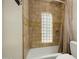 Close-up of a tiled shower and tub with glass block window and neutral-colored curtain at 4340 E Turquoise Ave, Phoenix, AZ 85028