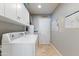 Well-lit laundry room with white cabinets and tiled flooring at 7844 E Coolidge St, Scottsdale, AZ 85251