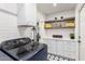 Clean laundry area showcases white cabinets, a utility sink, open shelving, tile backsplash, and modern appliances at 8708 E San Lucas Dr, Scottsdale, AZ 85258
