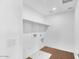 Bright laundry room with white walls, wood-look floors, built-in shelving and includes washer and dryer hookups at 9036 S 196Th Dr, Goodyear, AZ 85338