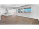 Bright open-concept living room featuring wood-look floors, white walls, a kitchen view, and large windows at 9036 S 196Th Dr, Goodyear, AZ 85338