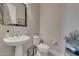 Elegant powder room with pedestal sink, toilet, and decorative accents at 18125 W Acacia Dr, Goodyear, AZ 85338