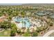 Expansive aerial view of the community pool area, tennis courts, and manicured lawns with palm trees at 27395 W Wahalla Ln, Buckeye, AZ 85396