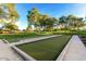 Well-maintained bocce ball courts with lush green surroundings and shaded seating areas for players at 27395 W Wahalla Ln, Buckeye, AZ 85396