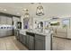 Bright kitchen boasts gray cabinets, stainless appliances, granite counters, and a large island with a farmhouse sink at 27395 W Wahalla Ln, Buckeye, AZ 85396
