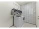 Well-organized laundry room features modern appliances, storage, and stylish wallpaper at 27395 W Wahalla Ln, Buckeye, AZ 85396