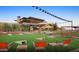 Outdoor area with a cornhole game on the lawn, inviting seating, and a building with modern architectural details at 27395 W Wahalla Ln, Buckeye, AZ 85396