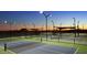 Illuminated pickleball courts at dusk, offering a fantastic recreational space for active residents to enjoy at 27395 W Wahalla Ln, Buckeye, AZ 85396