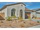 Front exterior of home with rock landscaping, arched window, tile roof, and neutral color scheme at 32034 N 125Th Ave, Peoria, AZ 85383