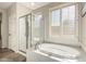 Luxurious bathroom featuring a soaking tub, glass-enclosed shower, and plantation shutters at 41216 N Shadow Creek Ct, Anthem, AZ 85086