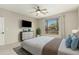 Serene bedroom with large window, neutral tones, ceiling fan and built-in media center with television at 41216 N Shadow Creek Ct, Anthem, AZ 85086