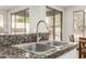 This kitchen sink features granite countertops, a stainless steel faucet, and a view to the backyard at 41216 N Shadow Creek Ct, Anthem, AZ 85086