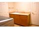 Neutral laundry room features a basin sink, natural wood cabinets, and a countertop for folding near the washing machine at 7712 S 25Th Ave, Phoenix, AZ 85041