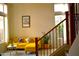 Bright living room with yellow sectional sofa, modern art, and a staircase with wrought iron spindles and wood handrail at 7712 S 25Th Ave, Phoenix, AZ 85041