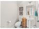 Stylish powder room featuring a pedestal sink, tiled floors, and a toilet, complemented by charming decor at 9523 E Sandy Vista Dr, Scottsdale, AZ 85262
