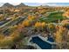 Aerial view of a luxurious pool with a waterfall, lounging area, and mature desert landscaping at 10801 E Happy Valley Rd # 102, Scottsdale, AZ 85255