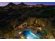 Aerial view of community pool, showcasing desert landscaping, night lighting, and mountain views for upscale living at 10801 E Happy Valley Rd # 102, Scottsdale, AZ 85255