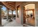 Elegant front entrance with stone pillars, desert landscaping, and an open wooden doorway at 10801 E Happy Valley Rd # 102, Scottsdale, AZ 85255