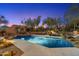 A luxurious pool at twilight features a waterfall, lounge chairs, and mature desert landscaping at 10801 E Happy Valley Rd # 102, Scottsdale, AZ 85255