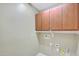 Laundry room with wooden cabinets and built-in shelving at 10813 W Saddlehorn Rd, Peoria, AZ 85383