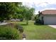 Manicured front yard with mature trees, lush lawn, and red tile roof, adding charm to the home at 4119 E Glencove St, Mesa, AZ 85205