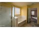 Bright bathroom featuring a soaking tub with tile flooring and a glass shower at 6455 W Orchid Ln, Glendale, AZ 85302