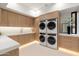 Modern laundry room with side-by-side washer and dryer, and custom cabinets at 6516 E Meadowlark Ln, Paradise Valley, AZ 85253