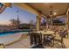 Inviting covered back patio featuring elegant outdoor furniture and a view of the sparkling pool and desert landscape at 7735 E Russell Cir, Mesa, AZ 85207