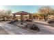 Community park featuring a covered gazebo with picnic tables, desert vegetation, and walking paths at 7735 E Russell Cir, Mesa, AZ 85207