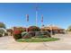 The Las Sendas Golf Club entrance with lush landscaping, flags, and charming buildings offers a warm welcome at 7735 E Russell Cir, Mesa, AZ 85207