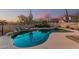 Luxurious pool area with a rock waterfall, desert landscaping, and a view of the surrounding neighborhood at 7735 E Russell Cir, Mesa, AZ 85207