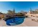 Inviting pool surrounded by desert landscaping including mature cacti, shrubs, and a tranquil rock waterfall feature at 7735 E Russell Cir, Mesa, AZ 85207
