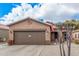 Tan house exterior with a brown garage door and desert landscaping at 830 E Tortoise Trl, San Tan Valley, AZ 85143