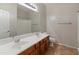 Bathroom featuring a double sink vanity, large mirror, and a shower with a white tile surround at 12541 W Miner Trl, Peoria, AZ 85383